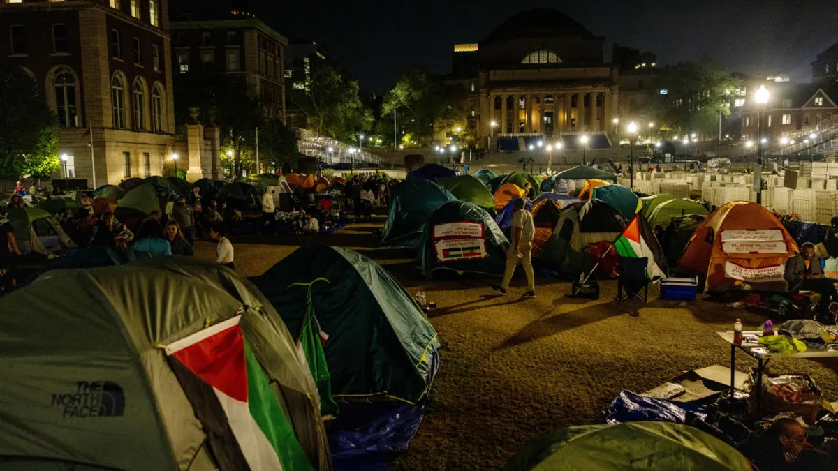 Students walk around a tent encampment on Columbia University's lawn.