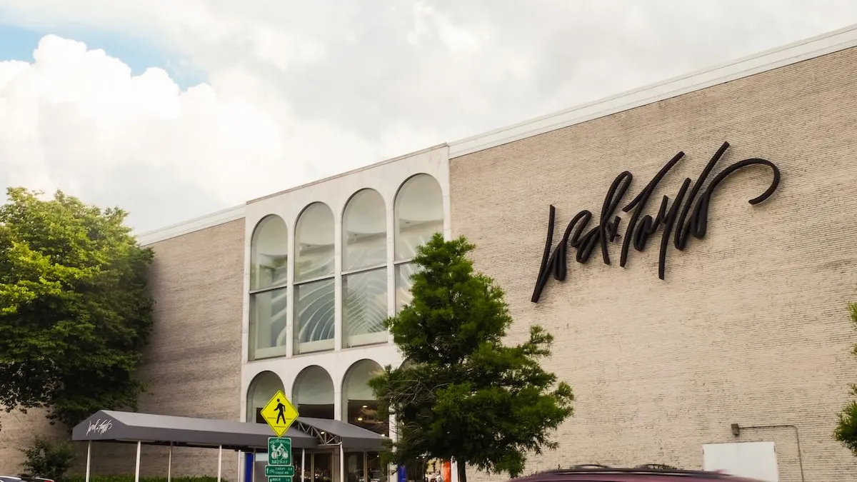 Puffy clouds and green trees frame a suburban department store building.