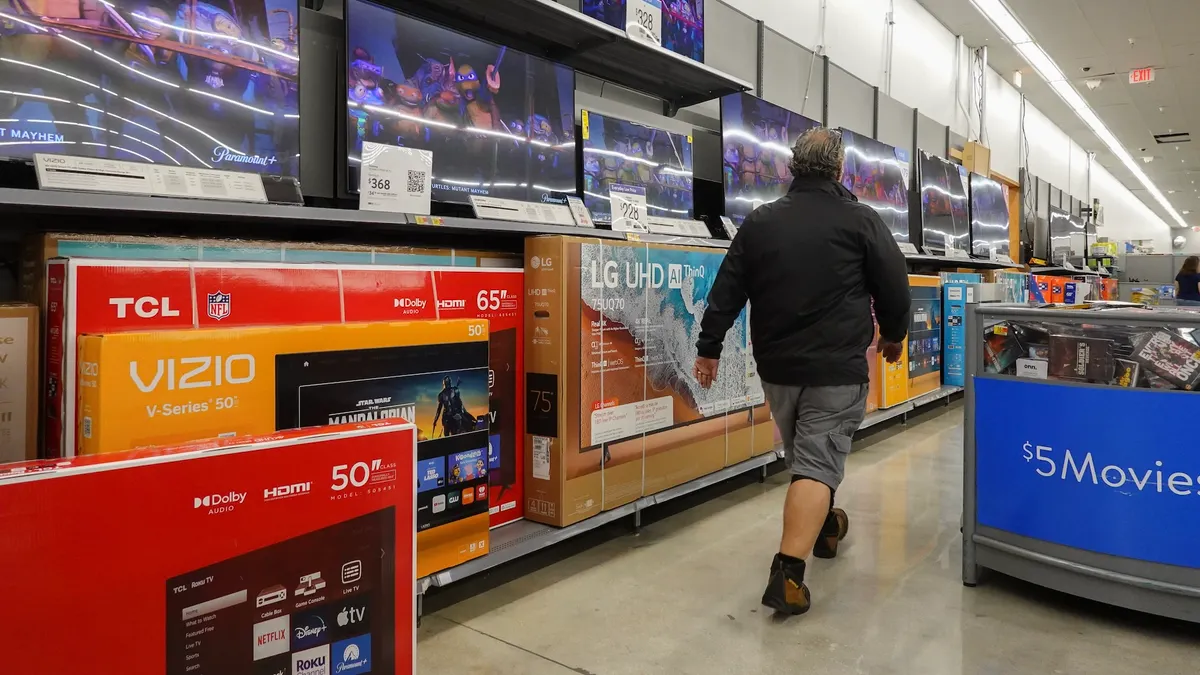 Vizio TVs in a Walmart as a person walks by