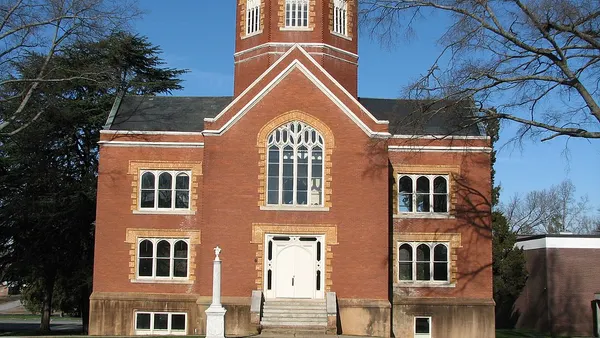 Brick building with a turret on top over grass field.
